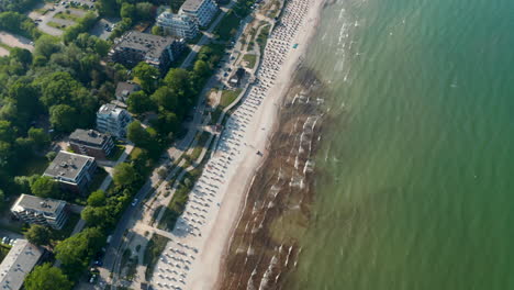 Sensational-travel-summertime-destination-high-aerial-view-of-tourist-beach-in-Baltic-sea-in-Scharbeutz,-Germany,-tilt-down-to-birds-eye-overhead-top-down-view,-day